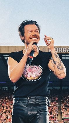 a man standing on top of a stage holding a microphone in front of a crowd