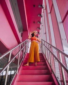 a woman in an orange dress is standing on some stairs