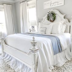 a white bed sitting in a bedroom next to two windows