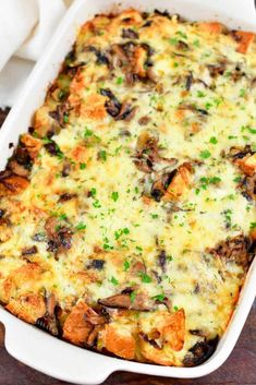 a casserole dish with cheese, mushrooms and parsley in it on a wooden table