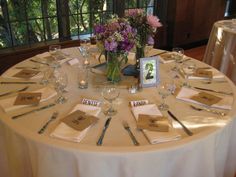 the table is set with silverware, place settings and flowers in vases on it