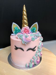 a pink cake decorated with unicorn ears and flowers