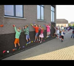 several children are climbing up the side of a building with their hands in the air