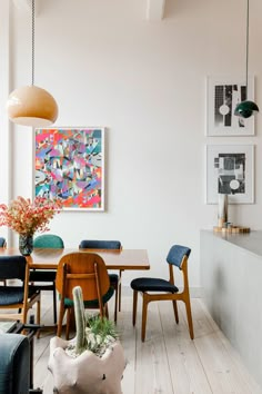 a dining room table with chairs and a painting on the wall in the back ground