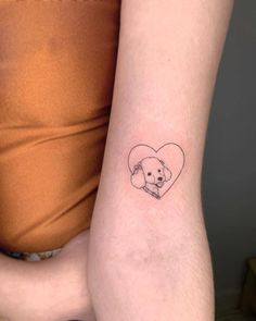 a woman's arm with a small tattoo of a dog in a heart on it