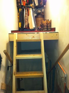 a ladder that is sitting in front of a shelf with clothes and shoes on it