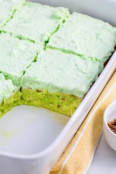 a cake in a pan with green frosting on top and two bowls next to it