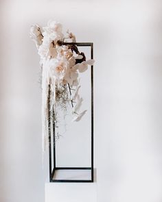 a white flower arrangement in a black metal frame