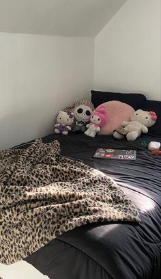 a bed with two stuffed animals on it in a room that has white walls and black sheets