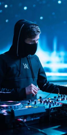 a man in a hoodie is mixing music on a dj's turntable