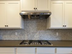 a stove top oven sitting inside of a kitchen next to white cabinets and cupboards