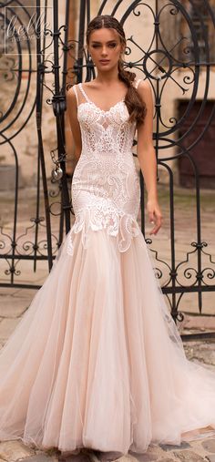 a woman standing in front of a gate wearing a wedding dress