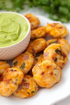 a white plate topped with tater tots next to a bowl of guacamole