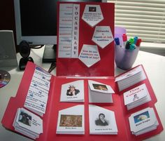 a red folder with pictures and other items on it sitting next to a computer monitor