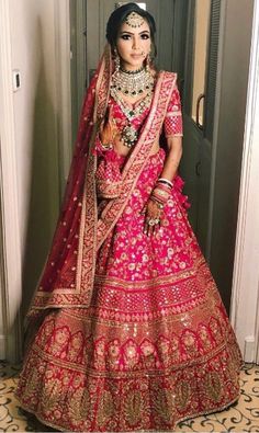 a woman in a pink and gold bridal gown standing next to a doorway with her hands on her hips