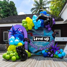 the balloon arch is decorated with balloons and streamers to spell out level up,