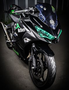 a black and green motorcycle is parked in the dark with its seat up on it's back end