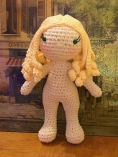 a crocheted doll sitting on top of a wooden table