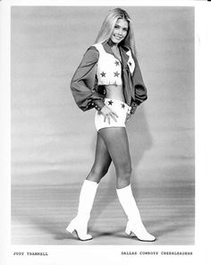 a black and white photo of a woman in cheerleader gear with her hands on her hips