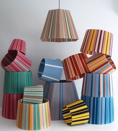 several different colored lamps hanging from the ceiling in front of a white wall and floor