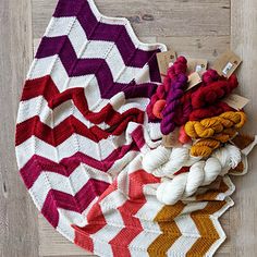 a pile of yarn sitting on top of a wooden floor next to a knitted rug