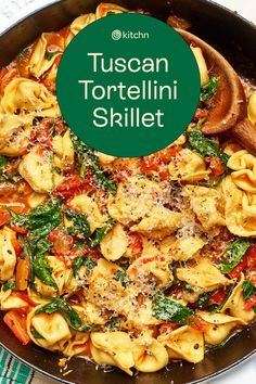 a skillet filled with tortellini shells and spinach on top of a table