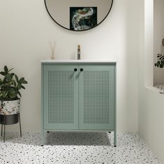 a bathroom with a green cabinet and potted plant on the floor next to it