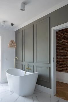 a large white bath tub sitting in a bathroom next to a brick wall and floor