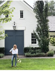 a woman standing in front of a white house