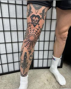 a person with tattoos on their legs and leg is standing in front of a wall