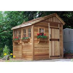 a small wooden shed with flower boxes on the roof and windows in it's side