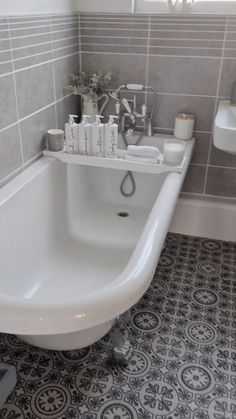 a white bath tub sitting in a bathroom next to a sink and toilet paper dispenser