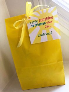 a yellow paper bag with a little sunshine on it and a thank you note attached