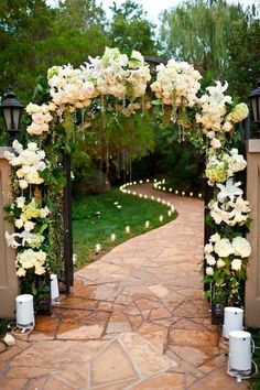 an archway decorated with white flowers and candles