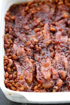 a casserole dish filled with meat and beans on top of a black table