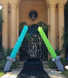 an entrance decorated with balloons and streamers in the shape of two green, white and blue trees