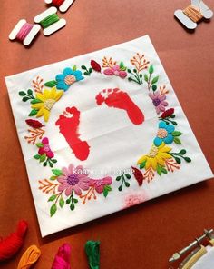 handprinted baby footprints and flowers on a table with crochet threads