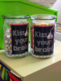 two glass jars with labels on them sitting on a counter next to a green bin