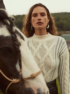 a woman standing next to a brown and white horse