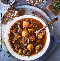 a white bowl filled with stew next to bread