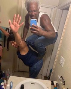 an older man taking a selfie in front of a mirror with his hands up