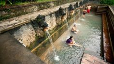 some people are sitting in the water near a fountain