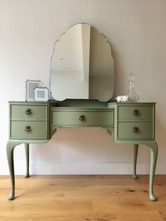 a green dresser with a large mirror on it's top and two drawers below