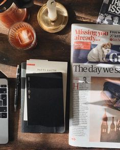 a table topped with magazines and a laptop computer next to a cup of coffee on top of a wooden table