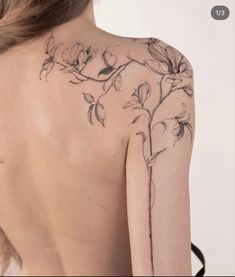 the back of a woman's shoulder with flowers tattooed on her left arm and chest