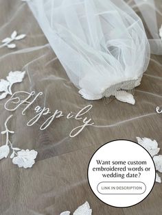 a wedding dress with white flowers on it and the words happily written in cursive writing