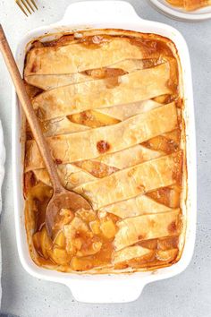 a casserole dish with sliced apples in it and a wooden spoon on the side