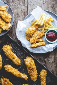 fried fish and fries on a pan with ketchup, french fries and dipping sauce