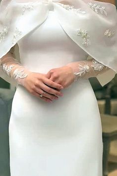 a woman wearing a white dress with an off the shoulder top and sleeves on her arms