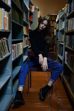 a woman sitting on a chair in a library